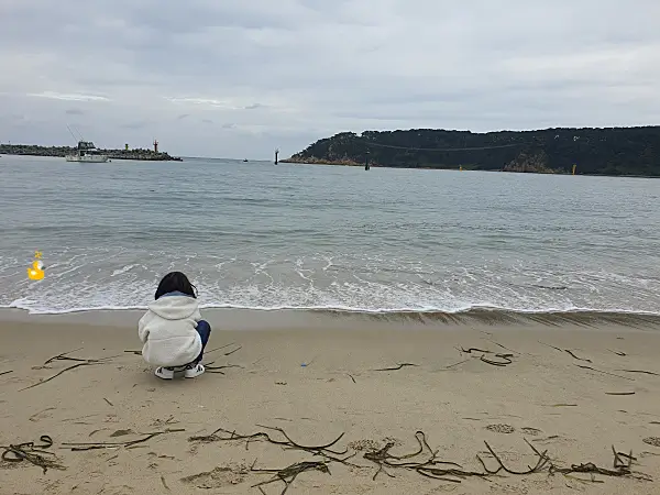 신발이 젖지 않을 만한 거리에서 바다를 바라보는 아이