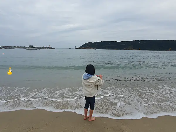 바지를 걷어 올리고 바닷가에서 노는 아이