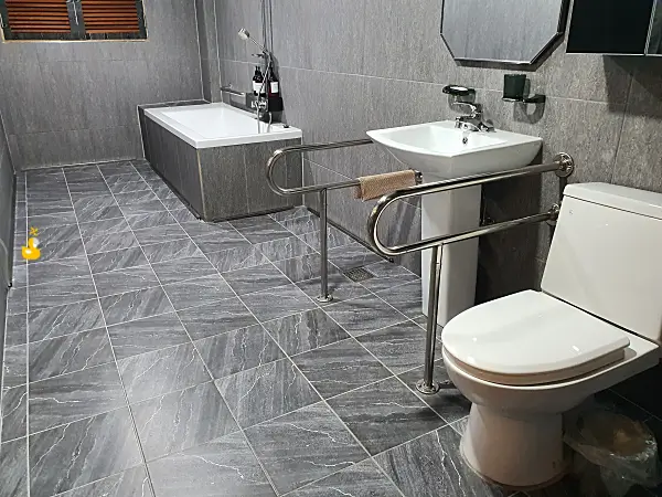 커다란 욕실에 장애인을 위한 난간이 설치된 세면대와 변기, 한쪽 끝에 놓인 욕조