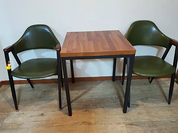 2인용 사각 테이블과 의자가 한쪽 벽에 붙어 놓여있는 사진