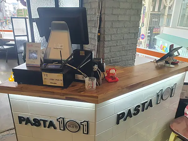 식당 안 계산대에 POS기와 온누리 결제QR코드, 농협 계좌 메모가 붙어있는 모습