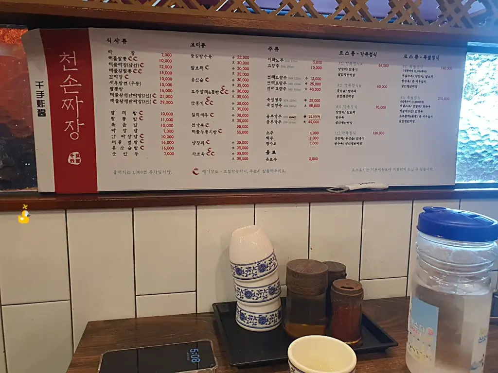 울산 무거동 맛집 천손짜장 테이블 옆에 붙어있던 메뉴판과 테이블마다 올려져 있던 컵과 양념