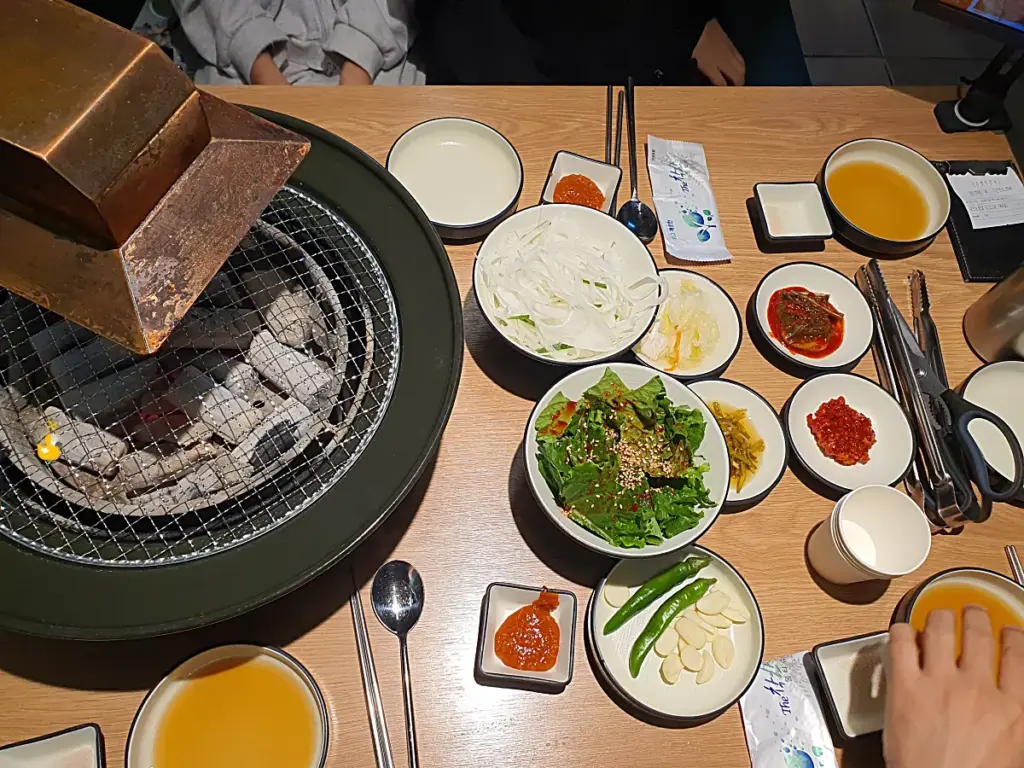 담가화로구이 무거점 기본 상차림으로 한쪽에 숯이 들어있는 화로와 갖가지 밑반찬이 올라가 있는 모습