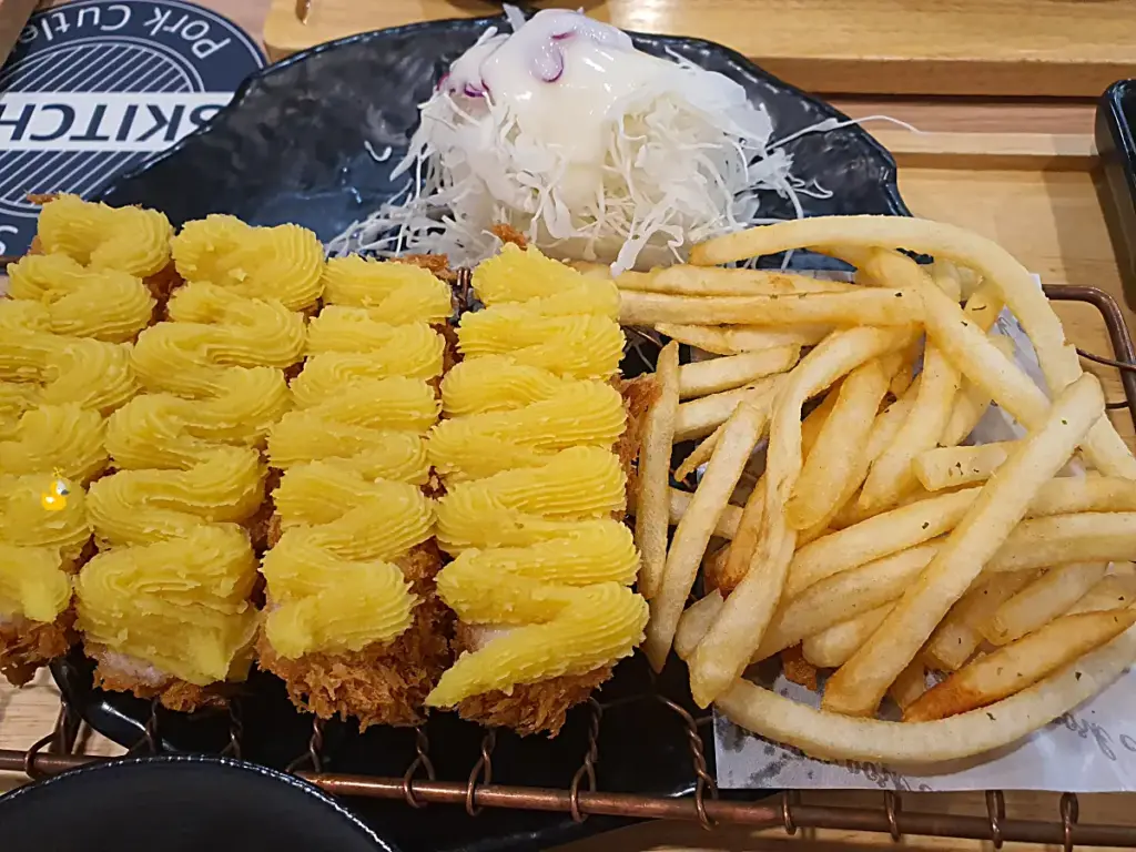 치즈 돈까스 위에 고구마 무스가 가득 올려져 있고 그 옆에 감자튀김, 양배추 샐러드가 놓여있는 모습