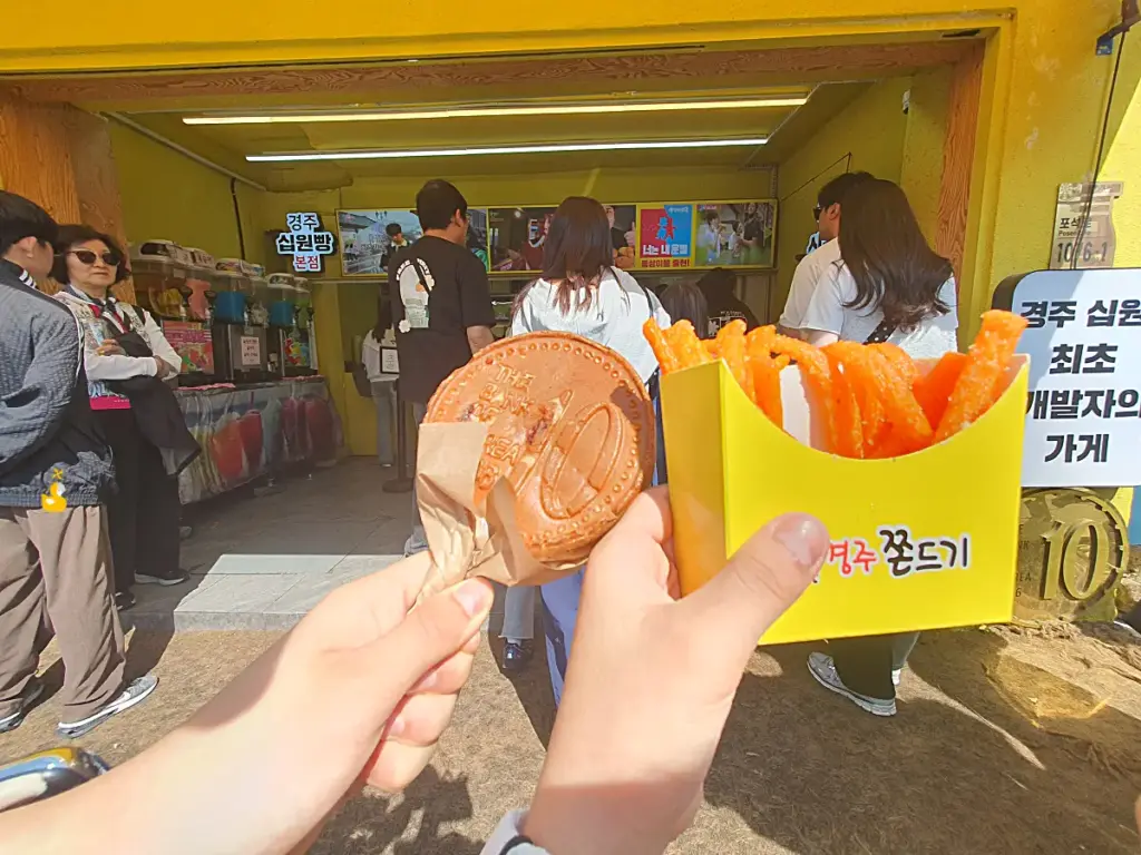 경주 황리단길 십원빵 가게 앞에서 십원빵과 쫀드기를 들고 있는 아이들 손